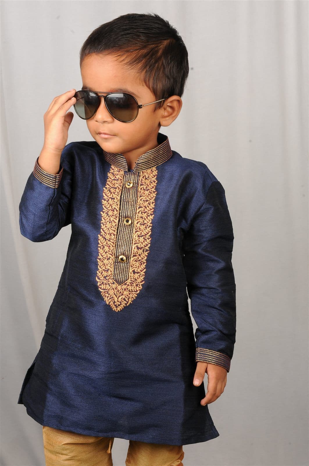 Studio portrait of Nihan in a navy embroidered kurta and sunglasses against a grey backdrop