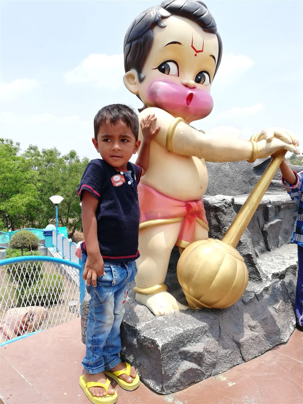 Nihan standing next to a giant cartoon statue in a park