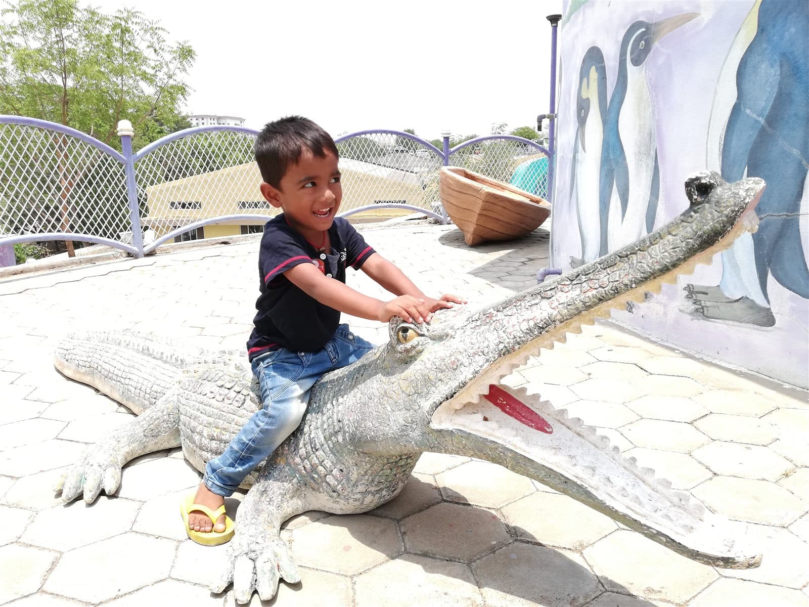 Nihan riding a crocodile statue in a park