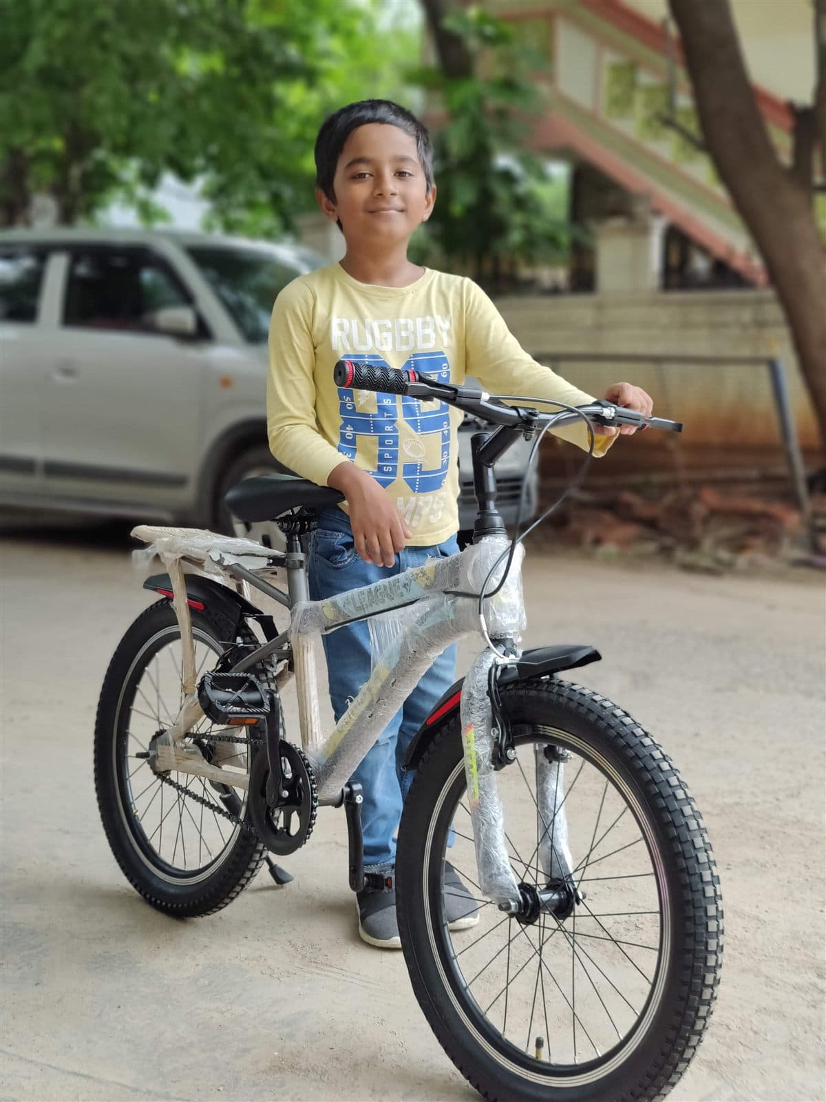 Nihan in a yellow tee standing with his bicycle on a street