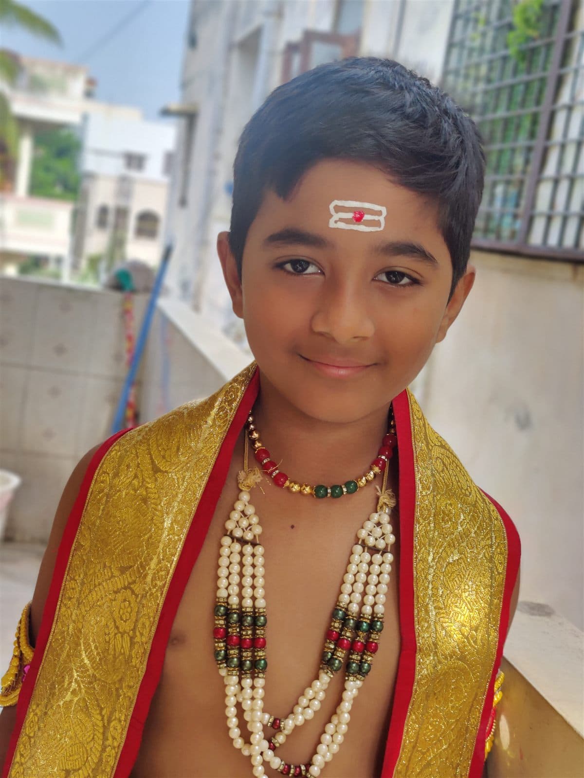 Festive close portrait of Nihan in a gold shawl and pearl necklaces with a tilak