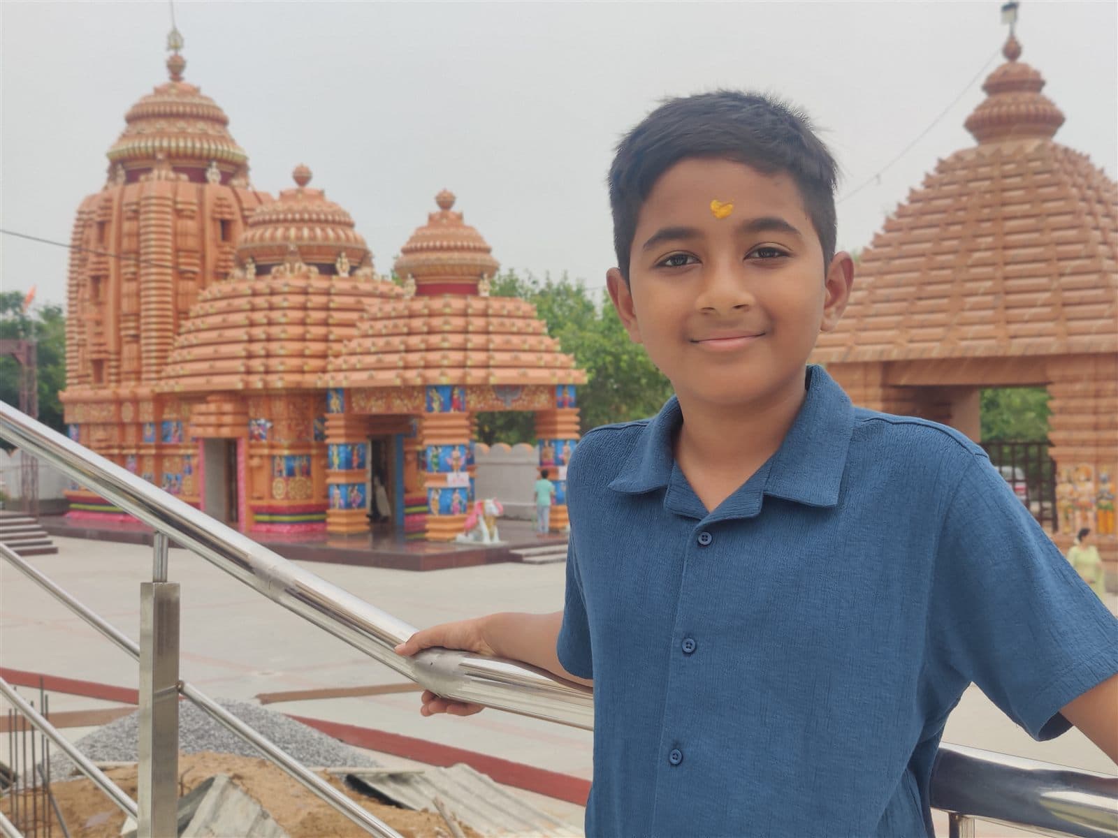 Nihan smiling in a blue polo in front of an ornate temple