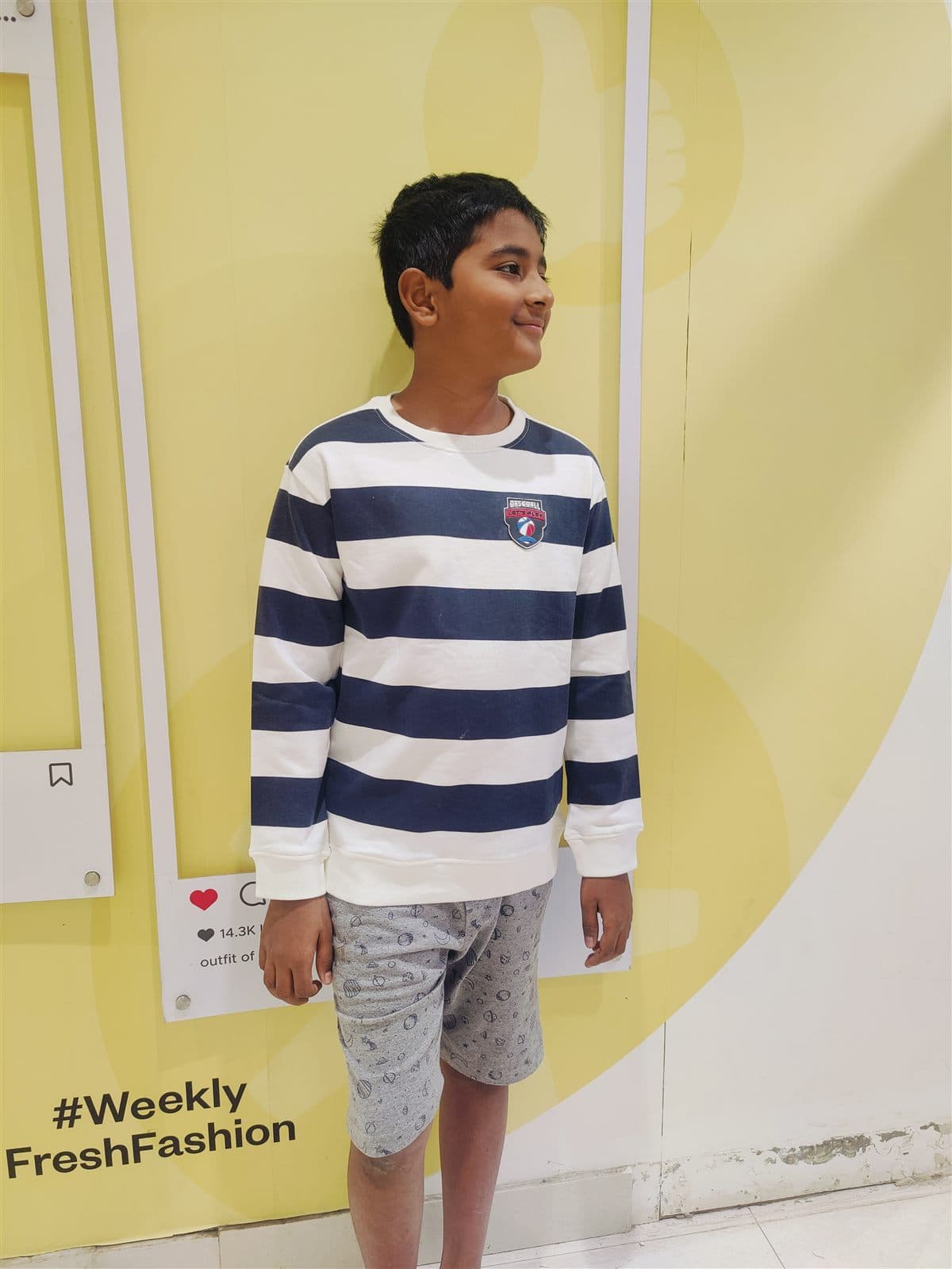 Nihan in a striped navy and white sweater against a yellow wall